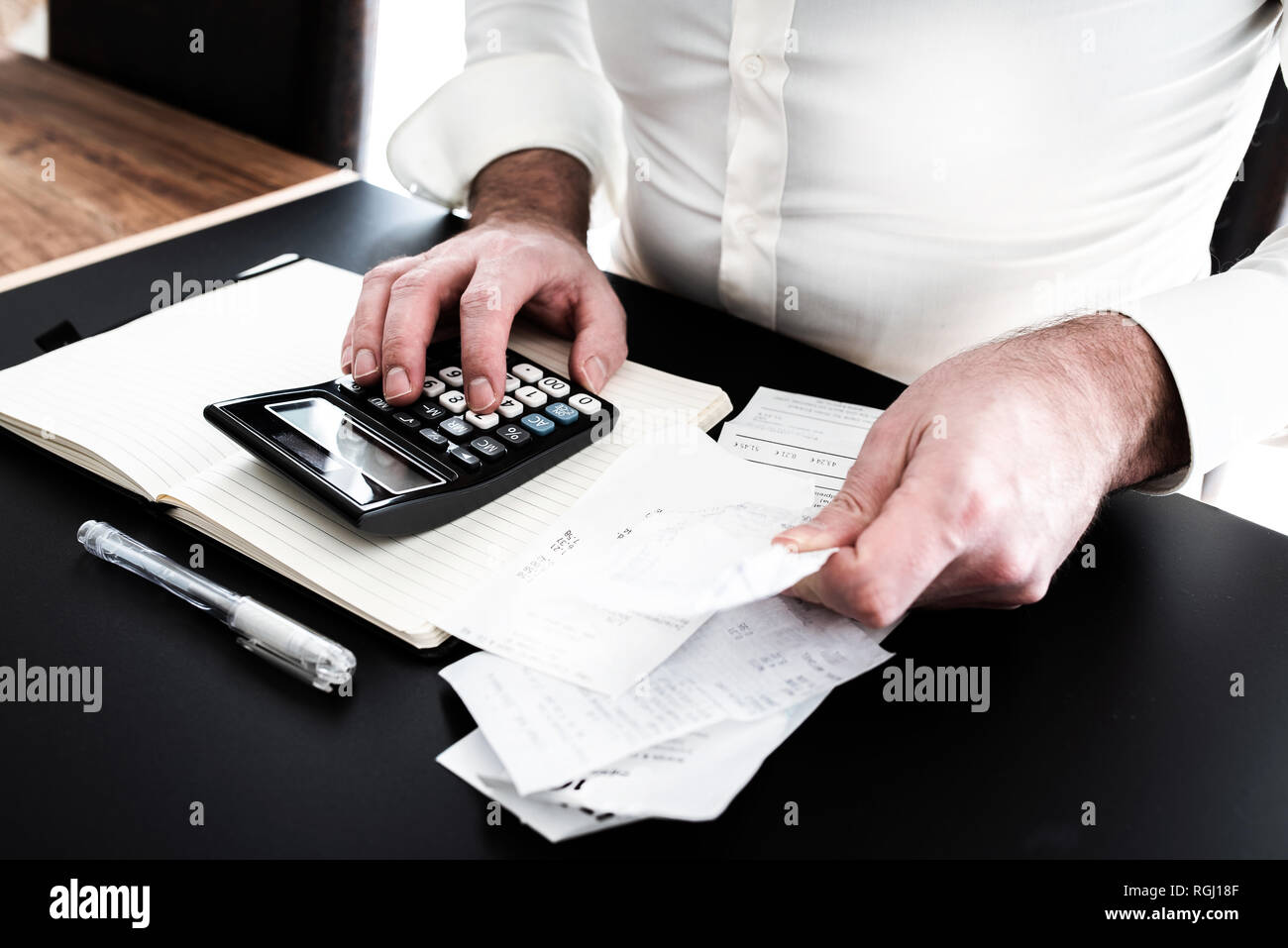 Mann an Schreibtisch mit Rechner, Wechsel oder Kaufbelege und Notpad Stockfoto