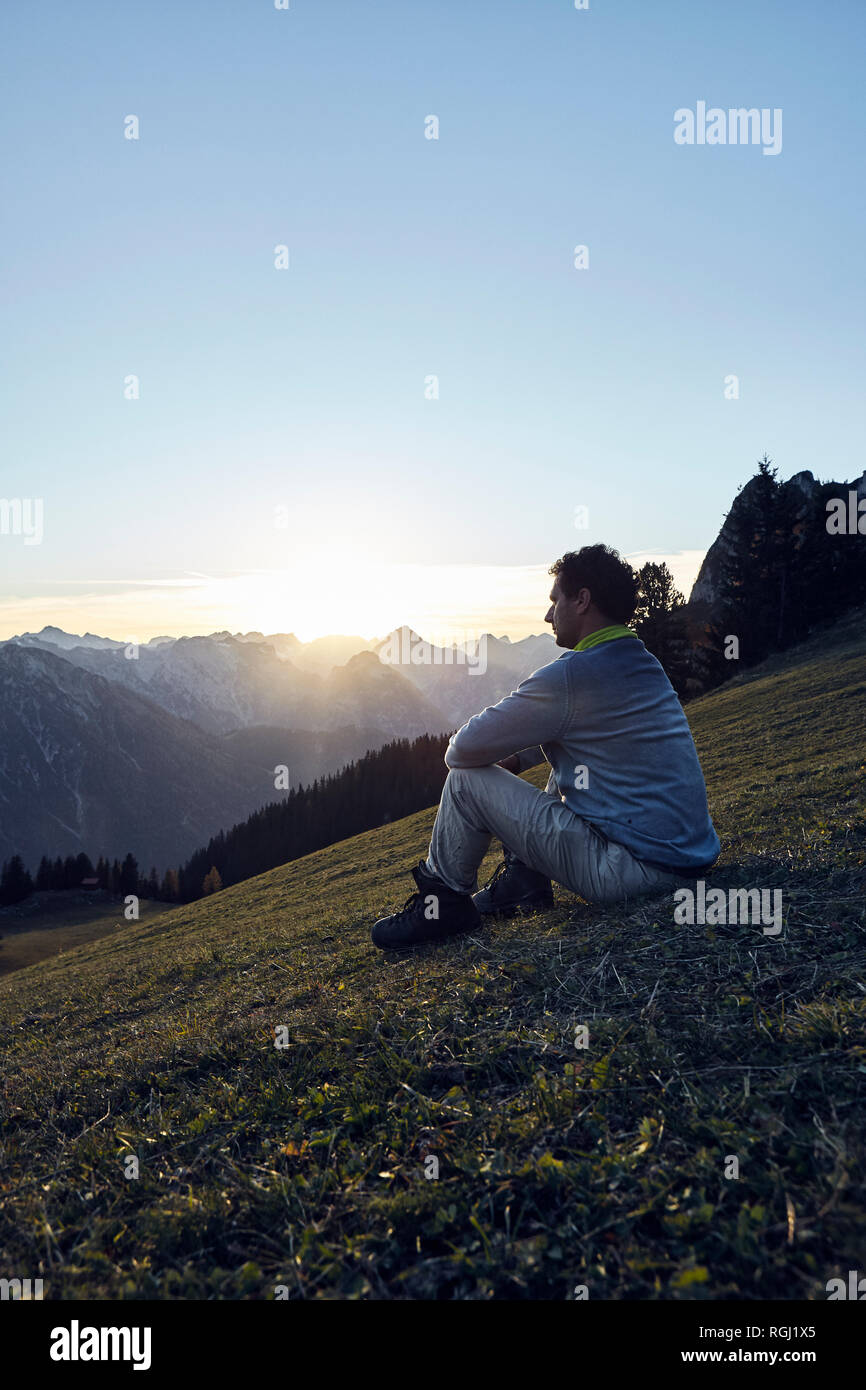 Österreich, Tirol, Rofangebirge, Wanderer sitzen auf Wiese bei Sonnenuntergang Stockfoto
