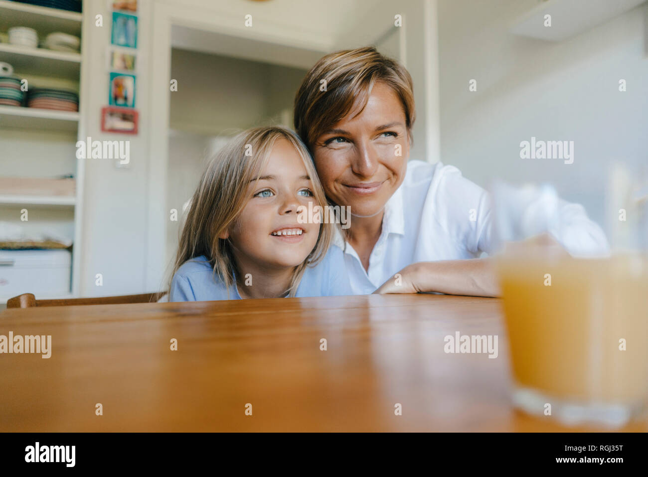 Lächelnde Mutter und Tochter in der Küche zu Hause sitzen Stockfoto