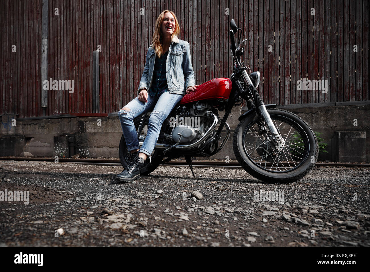 Lachende junge Frau mit Motorrad Stockfoto