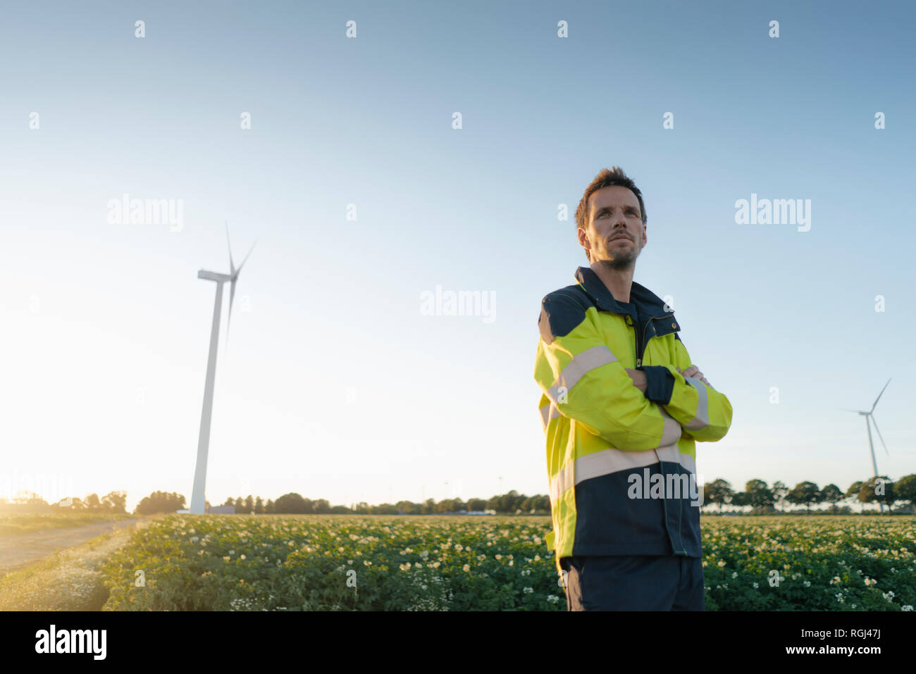 Techniker stehen in einem Feld zu einer Windenergieanlage Stockfoto