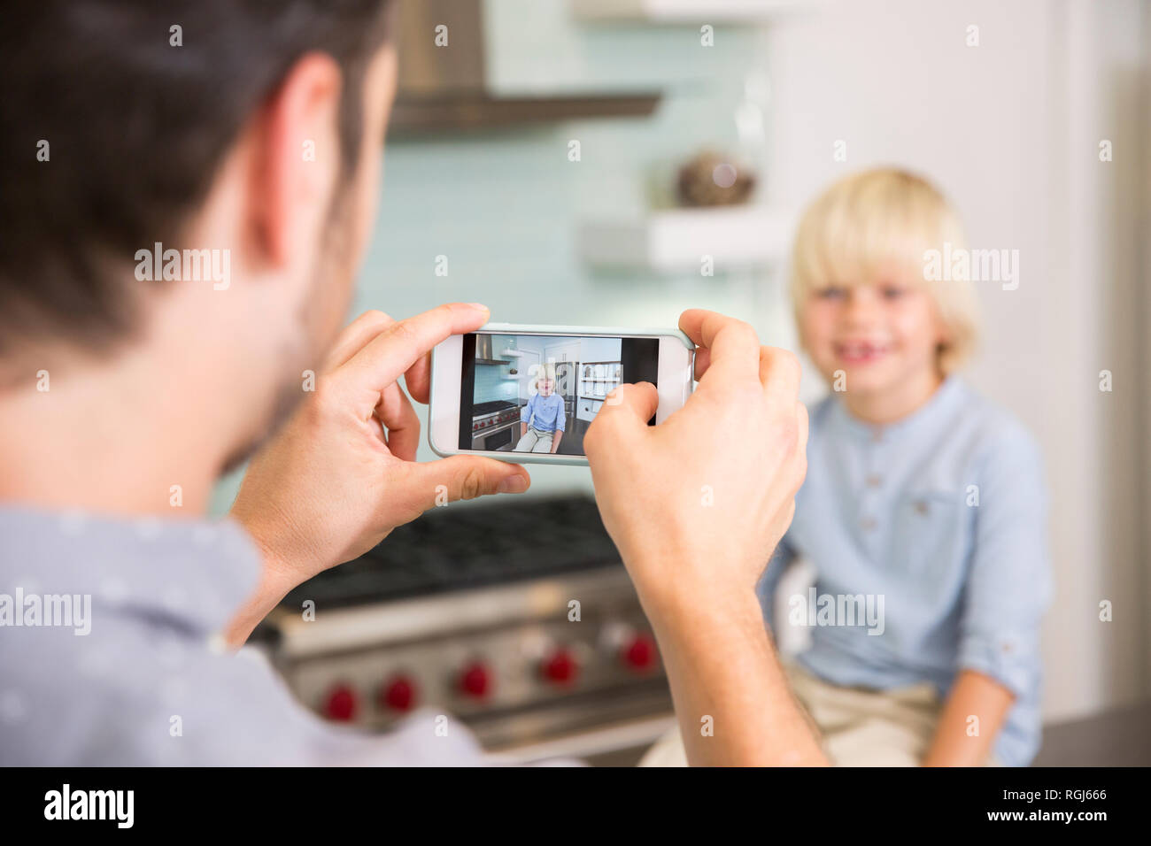 Vater unter Handy Bild der Sohn in der Küche Stockfoto