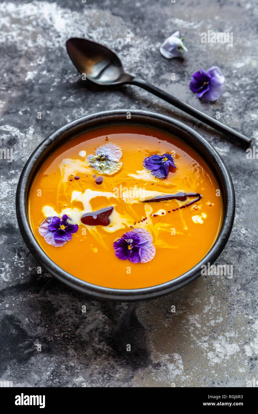 Schüssel cremige Kürbissuppe mit essbaren Blüten garniert Stockfoto