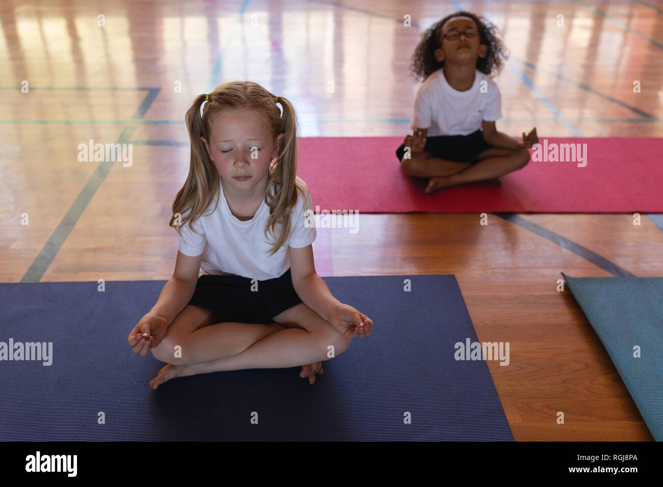 Schoolkids Yoga und Meditation über Yoga Matte in der Schule Stockfoto