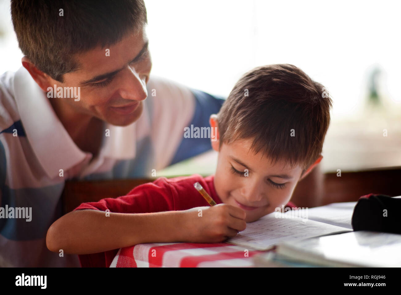 Vater helfen, seinen Sohn mit seinen Hausaufgaben auf einen Tisch. Stockfoto