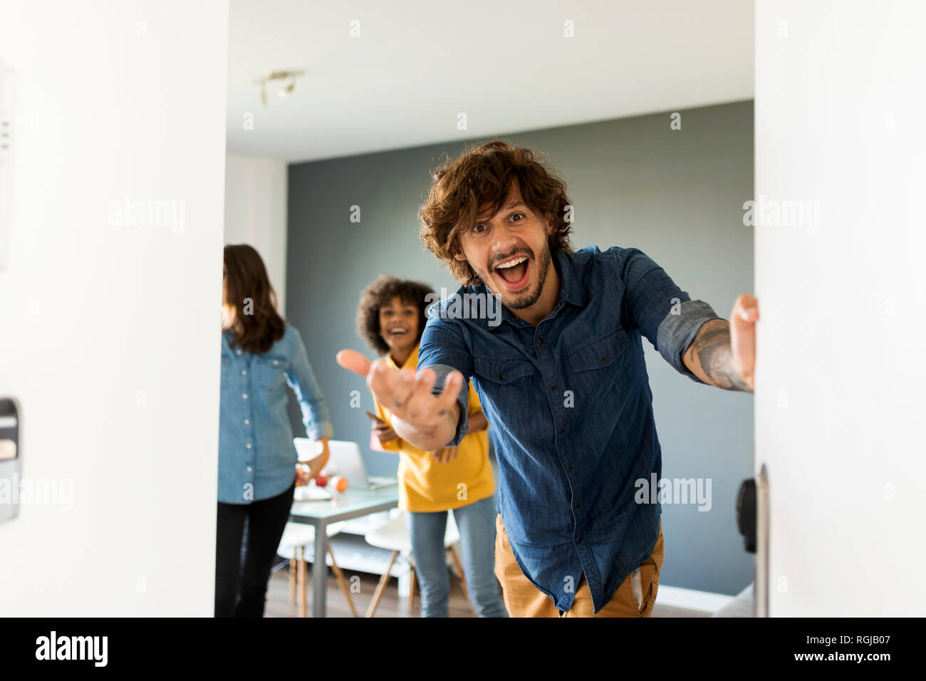 Portrait von überrascht man mit Freunden im Hintergrund öffnen der Tür Stockfoto