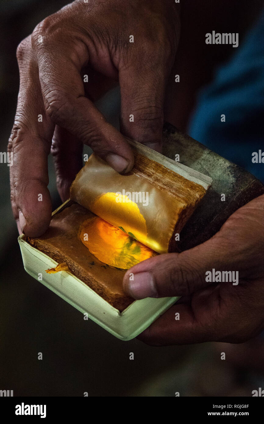 Eine Hand flicks durch ein Buch von Mitte Produktion Blattgold in der traditionellen Weise in Mandalay, Myanmar. Stockfoto