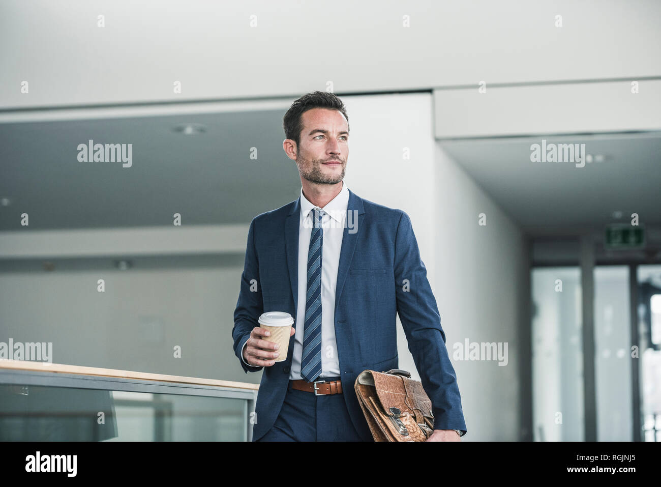 Geschäftsmann mit Aktenkoffer wandern in Bürogebäude, Tasse Kaffee Stockfoto