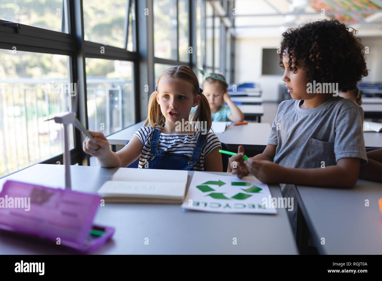 Vorderansicht des Schüler diskutieren über Mühle Modell am Schreibtisch im Klassenzimmer der Volksschule Stockfoto