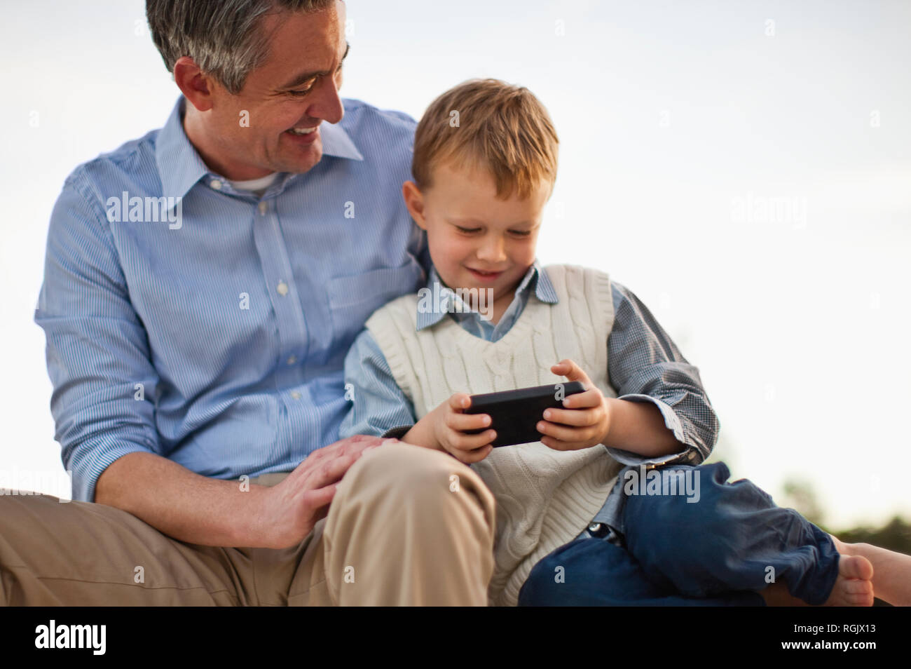Junge neugierig spielen mit Handy seines Vaters. Stockfoto
