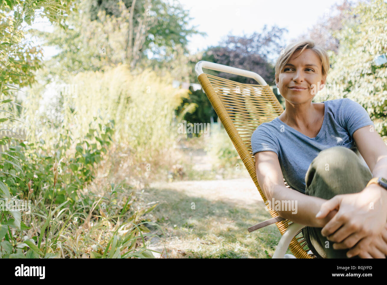 Frau sitzt im Garten am Lehrstuhl Stockfoto