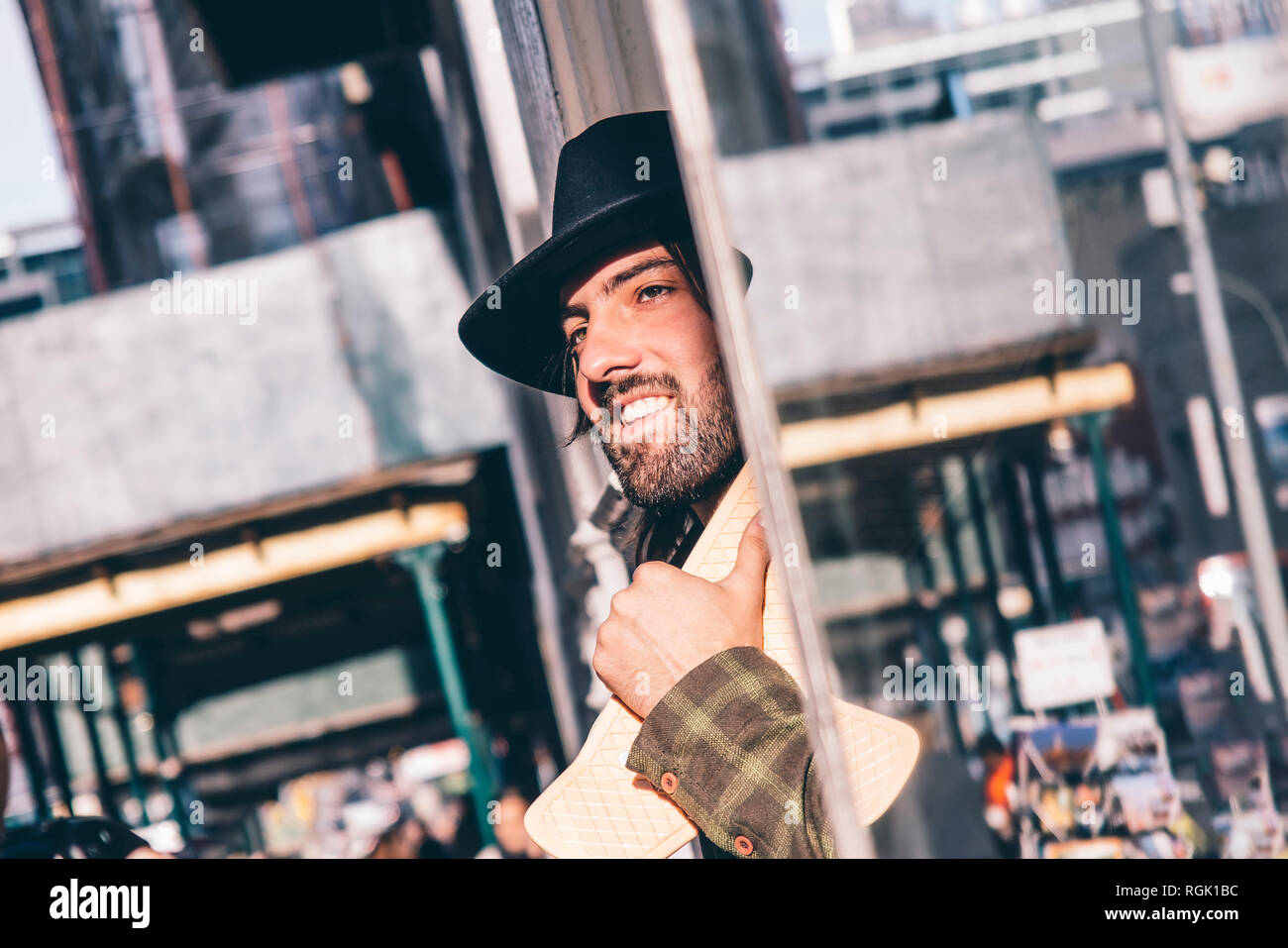 USA, New York City, Portrait eines bärtigen Mannes mit Skateboard mit schwarzen Hut Stockfoto