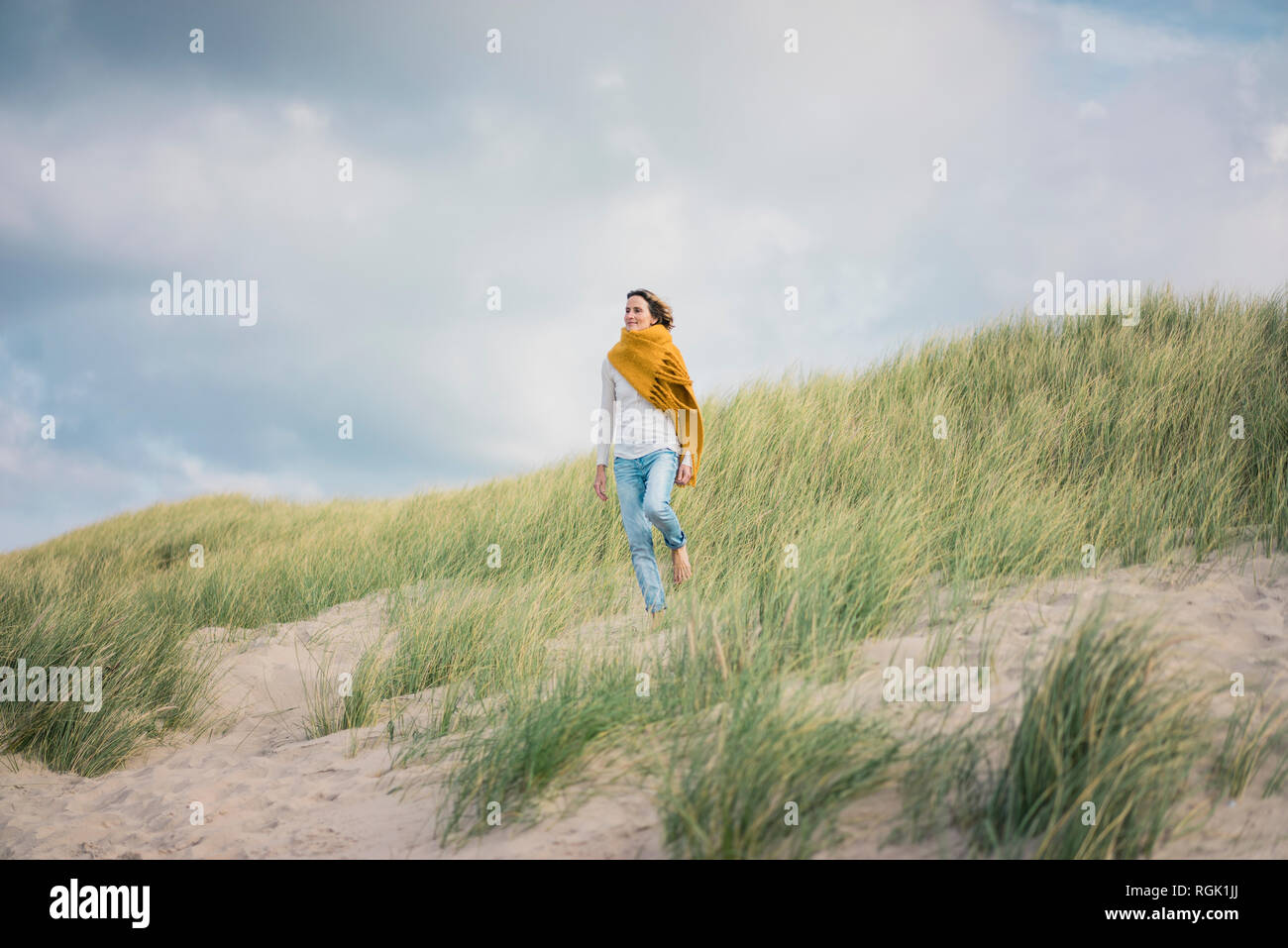 Reife Frau entspannen in den Dünen, genießen den Wind Stockfoto
