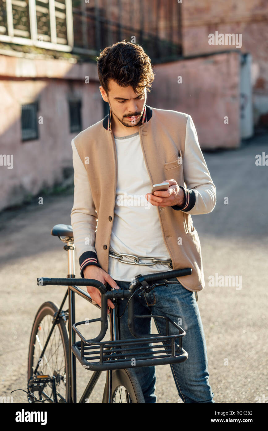 Junger Mann mit Pendler fixie Bike auf einem Hinterhof in der Stadt prüfen Handy Stockfoto