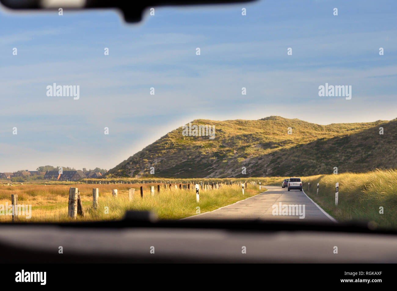 Blick aus einem Auto mit einem kleinen Hügel vor sich auf eine Reise entlang der Küste von Sylt. Stockfoto