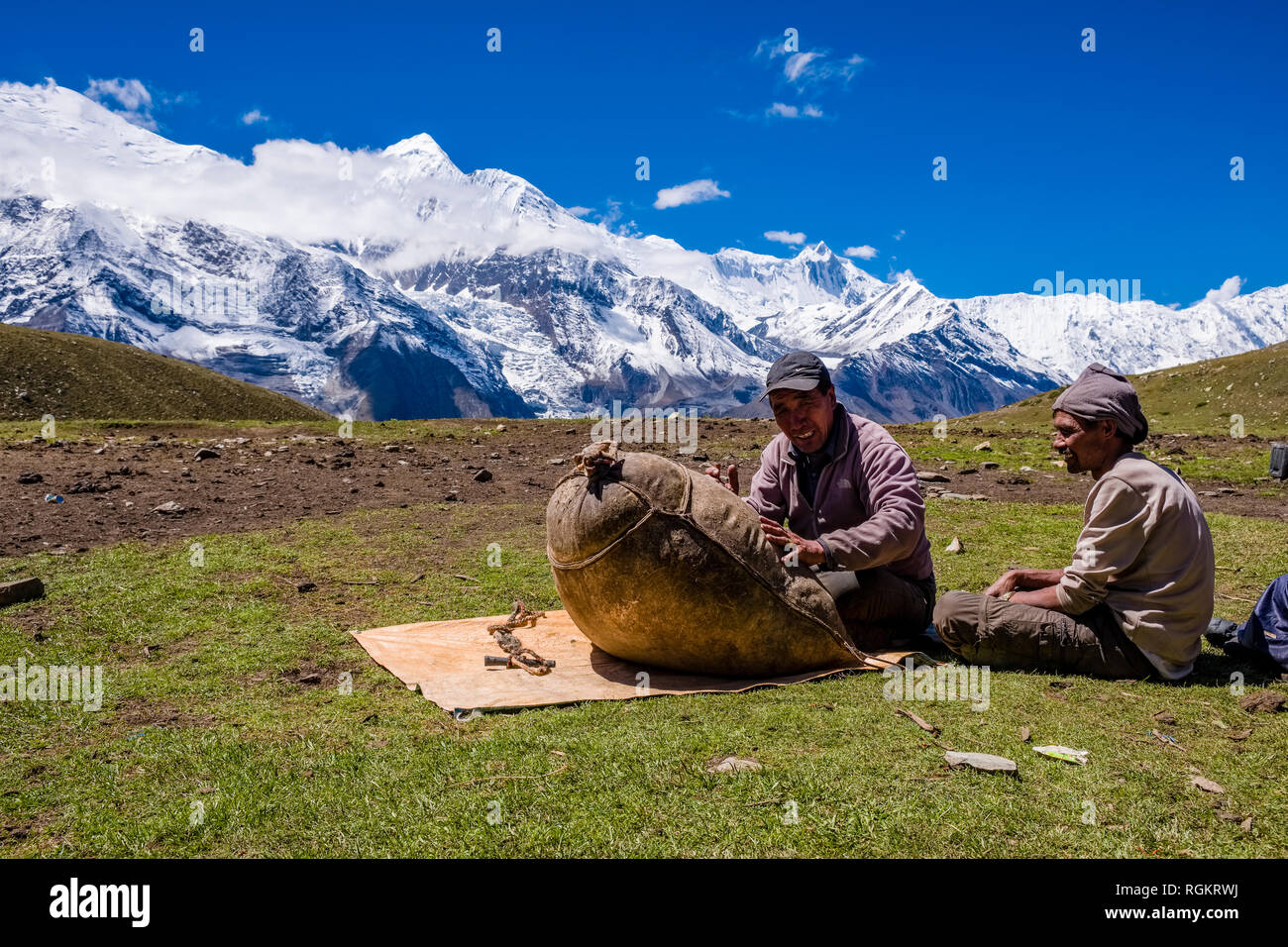 Zwei Männer machen Yak Butter in Ice Lake, der Schnee Gipfel der Annapurna in die zurückgelegte Strecke Stockfoto