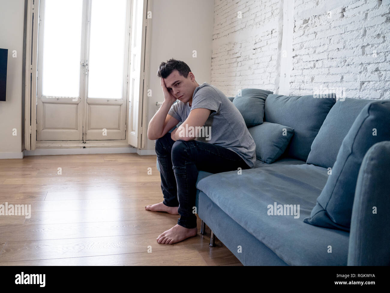 Portrait des jungen Mannes felling deprimiert und hoffnungslos allein weinend in Sofa home Leiden emotionalen Schmerz und Unglück. In den Leuten gebrochenes Herz, Bull Stockfoto