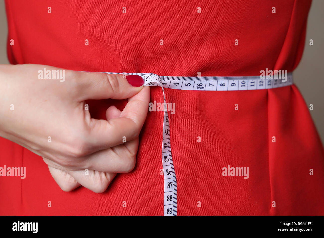 Diät Konzept, eine Frau im roten Kleid mit Maßband um die Taille. Gewichtsreduktion, abnehmen, Gesundheit Stockfoto