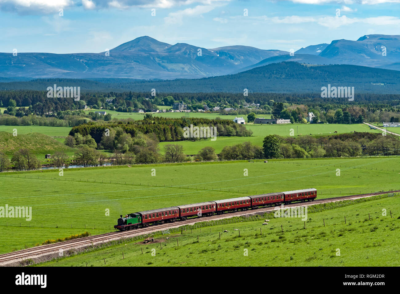 Dampfmaschine Braeriach hat in Broomhill Station auf der Strathspey Railway vom Boot von Garten mit Cairngorm Mountains im Hintergrund angekommen Stockfoto