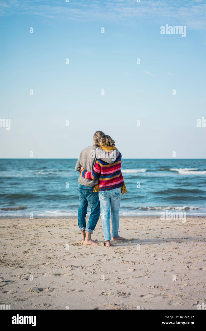 Ture Paar stehend auf den Strand mit den Armen herum, mit Blick auf das Meer Stockfoto
