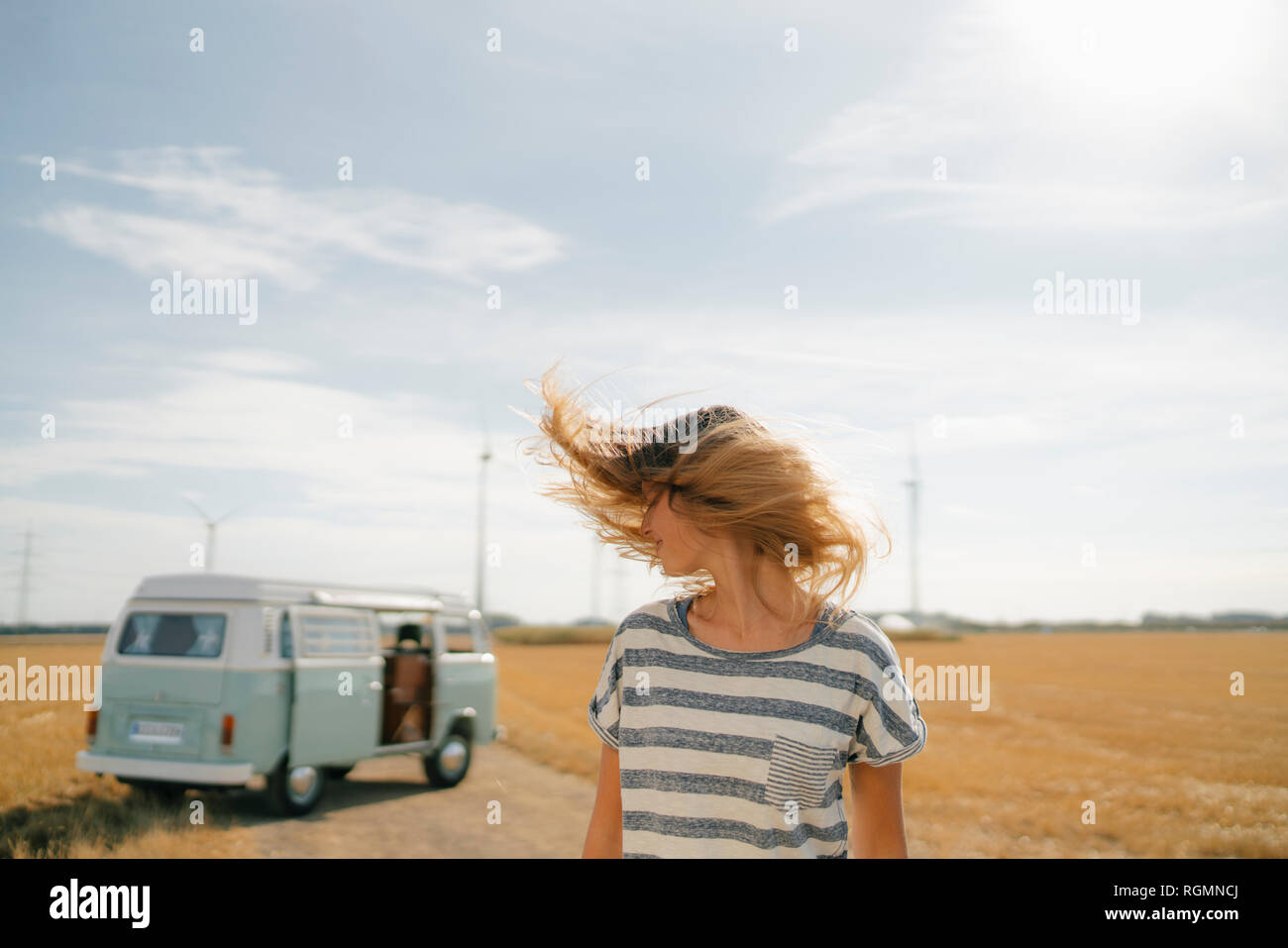 Blong junge Frau von Camper van in ländlichen Landschaft schütteln ihr Haar Stockfoto