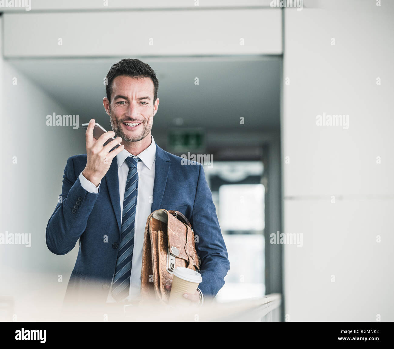 Geschäftsmann mit Aktenkoffer wandern in Bürogebäude, mit Smartphone Stockfoto