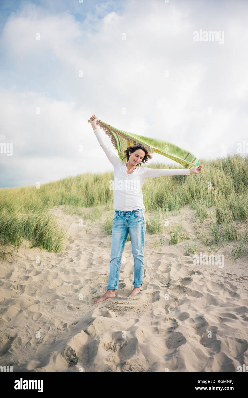 Reife Frau mit flatternden Schal im Wind, relxiang in den Dünen Stockfoto