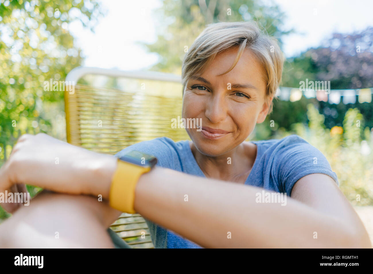 Portrait von lächelnden Frau sitzt im Garten am Lehrstuhl Stockfoto