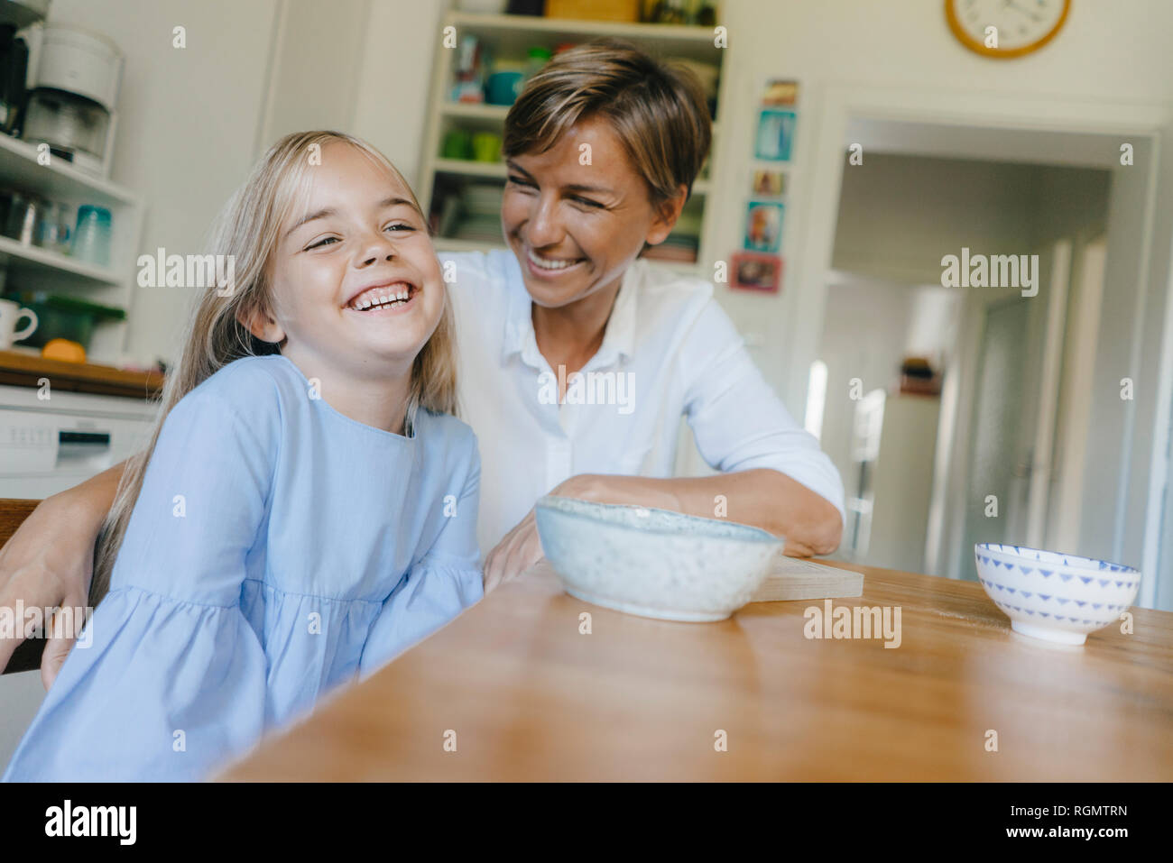 Glückliche Mutter und Tochter sitzen am Küchentisch zu Hause Stockfoto