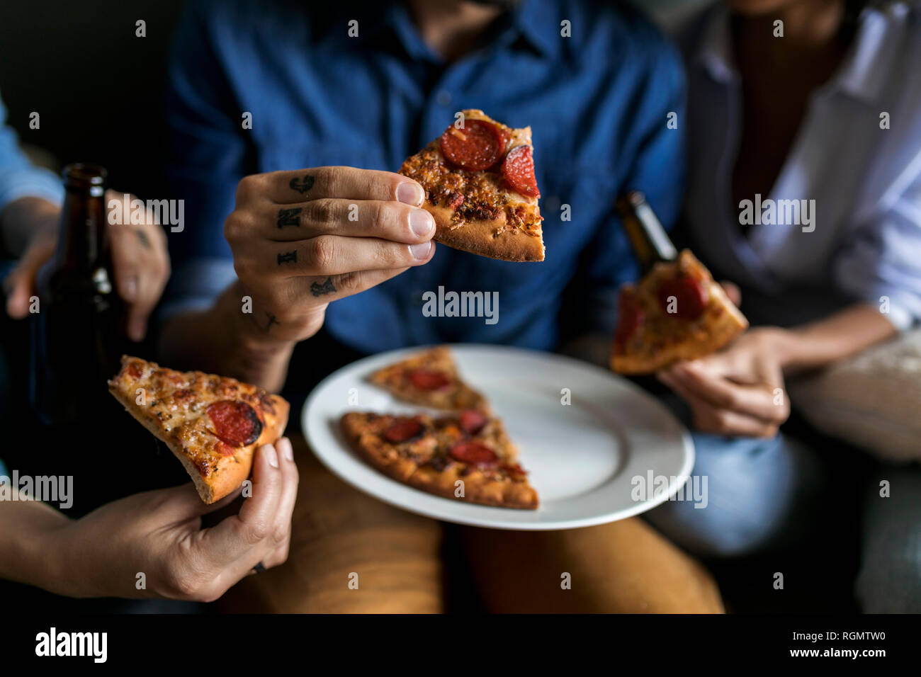 Nahaufnahme der tätowierten Mann mit Freunden holding Pizza Stockfoto