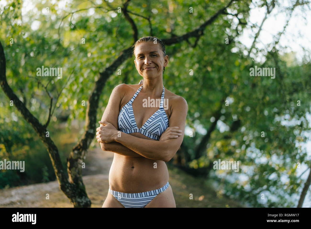 Porträt der lächelnde Frau trägt einen Bikini an einem See Stockfoto