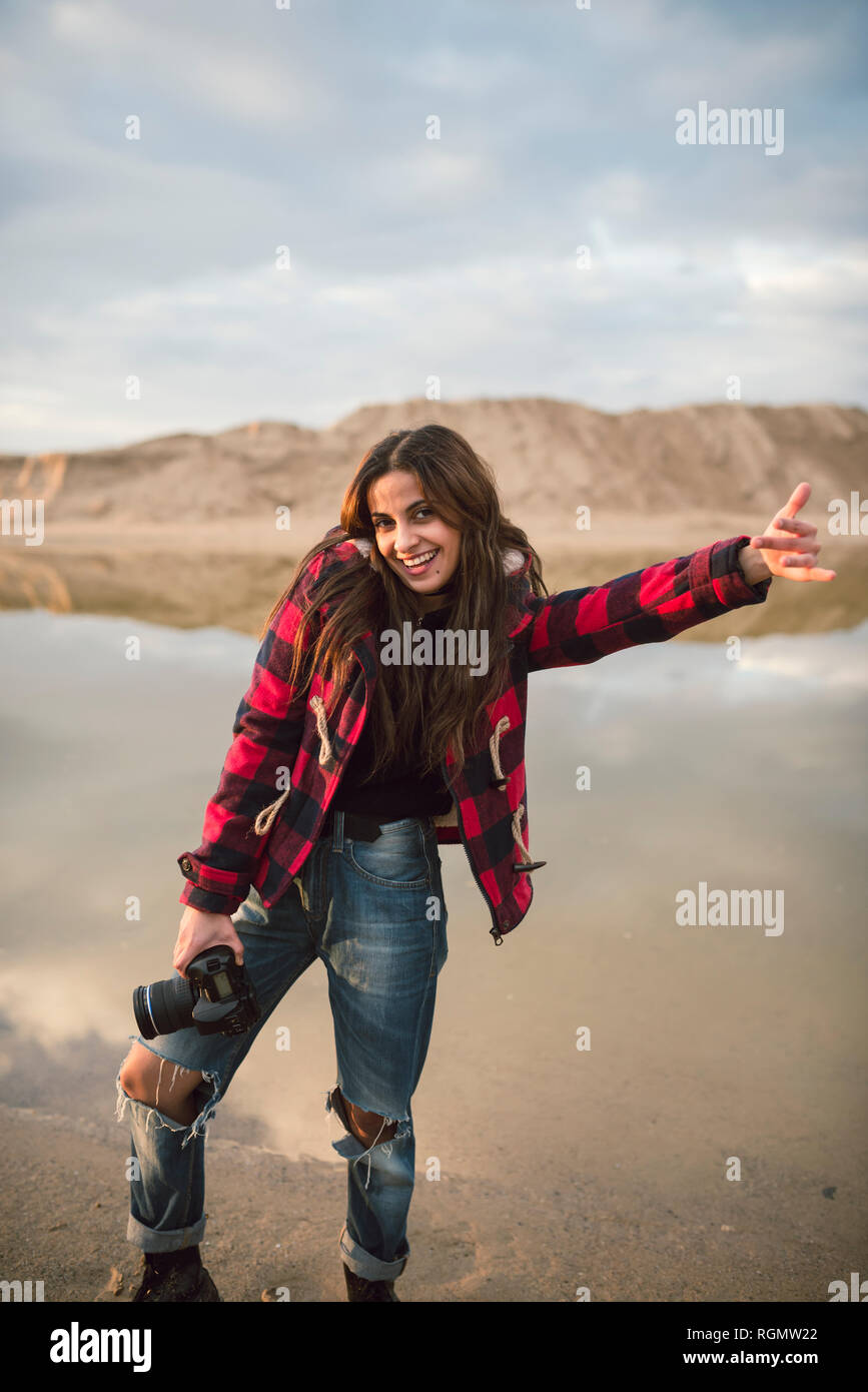 Portrait von Lachende junge Frau mit Kamera am Strand Stockfoto