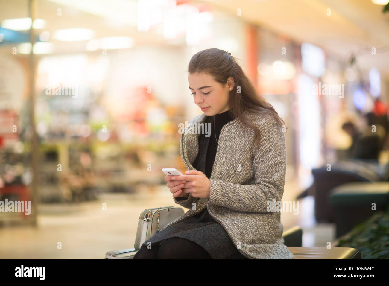 Junge Frau mit Smartphone im Shop Stockfoto
