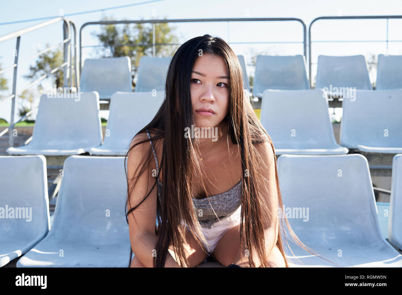 Porträt der jungen Frau sitzt auf der Tribüne des Stadions Stockfoto