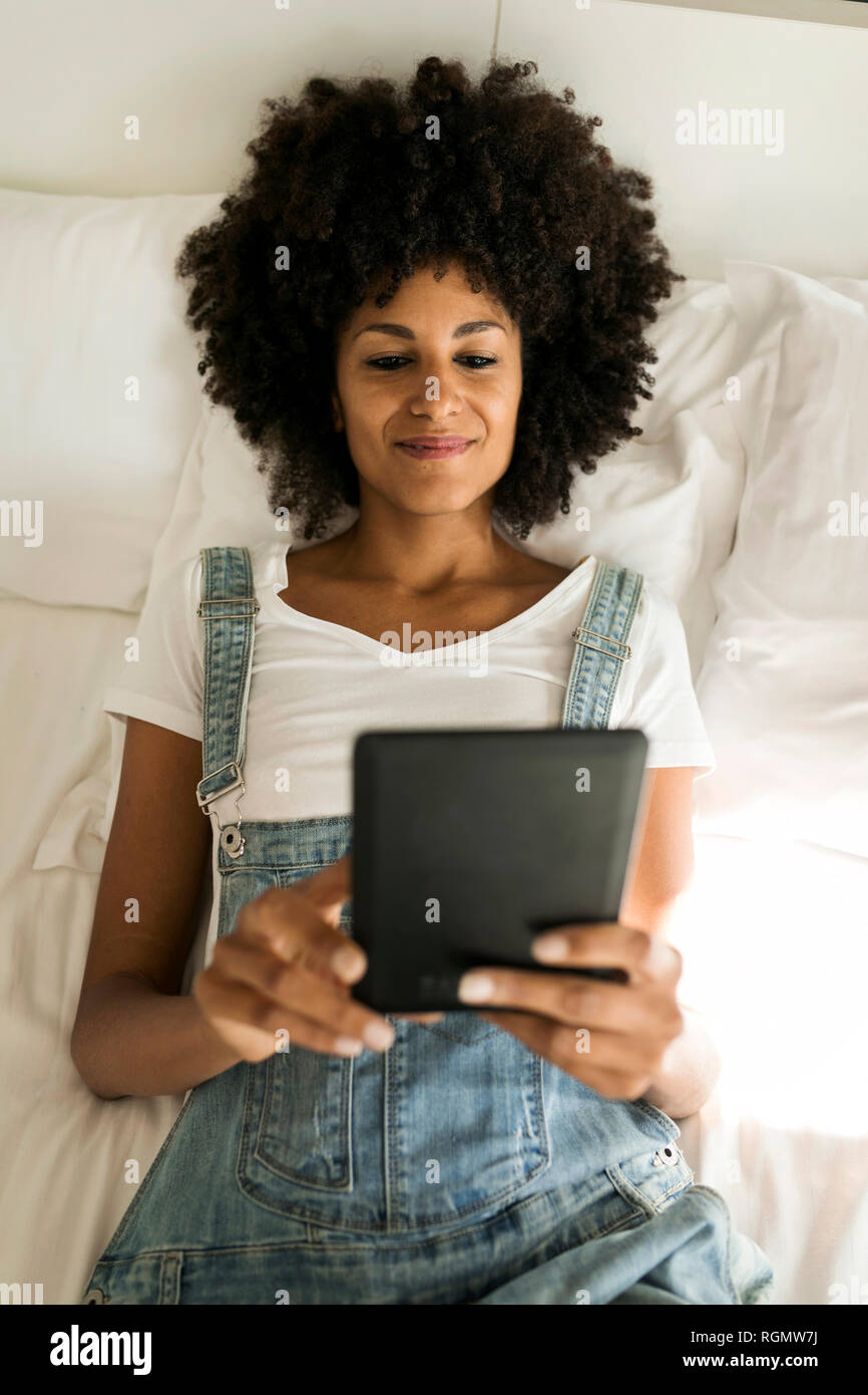 Lächelnde Frau liegen im Bett lesen e-book Stockfoto
