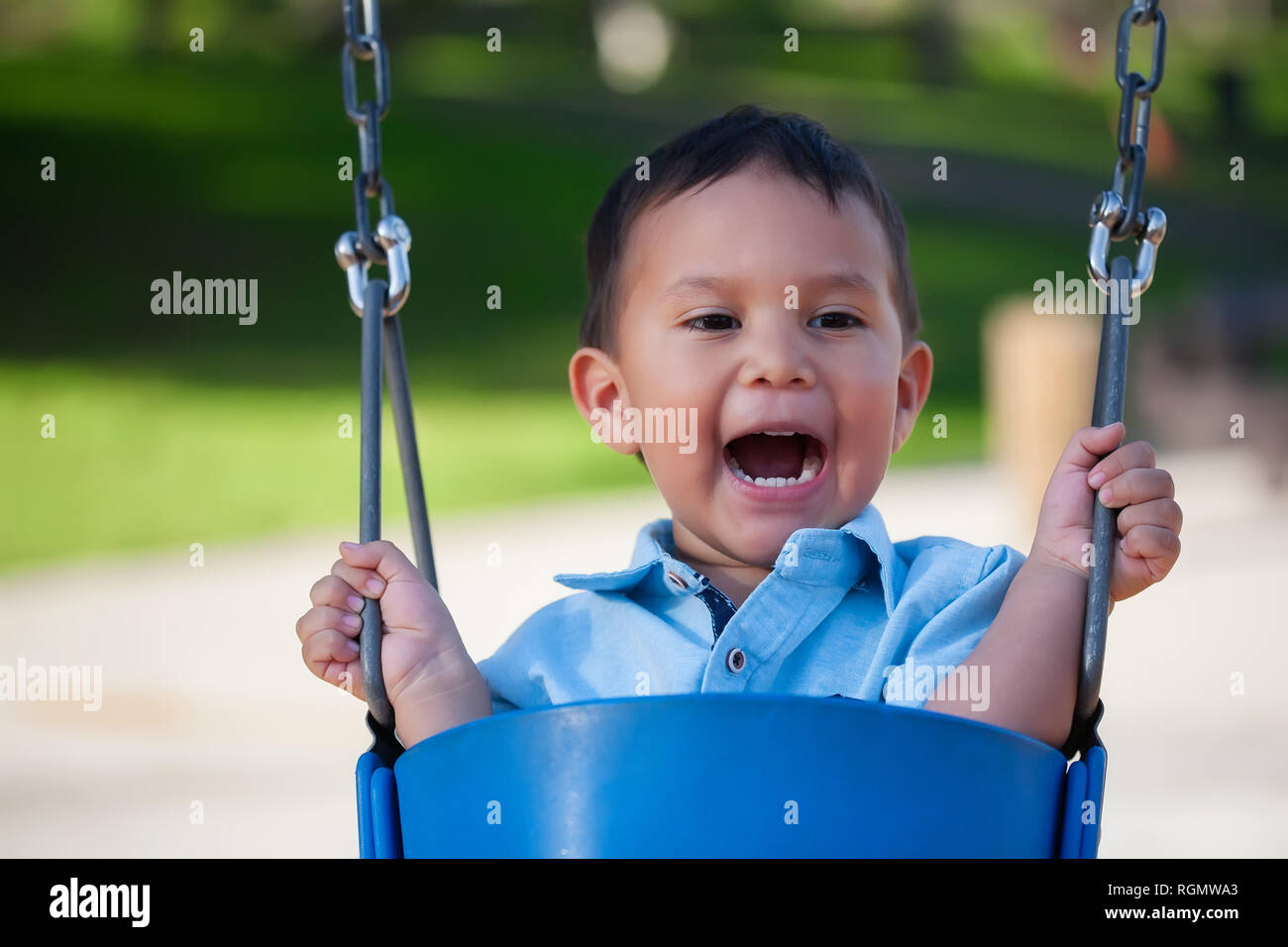 2 Jahre alter Junge laut schreien beim Reiten eines blauen Schwingen an einem lokalen Park. Stockfoto