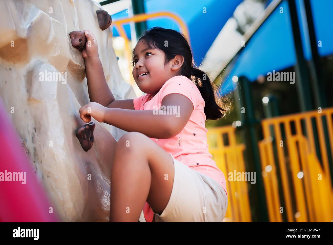 Jung und körperlich aktive indische Mädchen über ihre Stärke eine Kletterwand zu erobern. Stockfoto