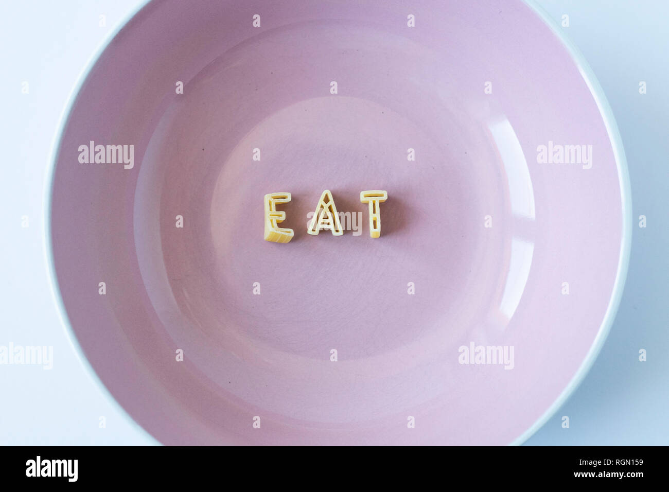 Das Wort "Essen" mit echten pasta Buchstaben in einem rosa Schale. Stockfoto