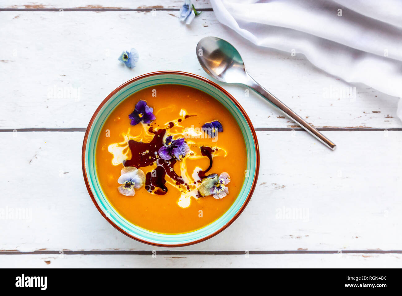 Schüssel cremige Kürbissuppe mit essbaren Blüten garniert Stockfoto