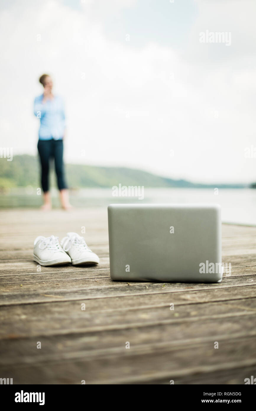 Laptop Und Schuhe Auf Dem Steg Am See Mit Frau Im Hintergrund Stockfotografie Alamy