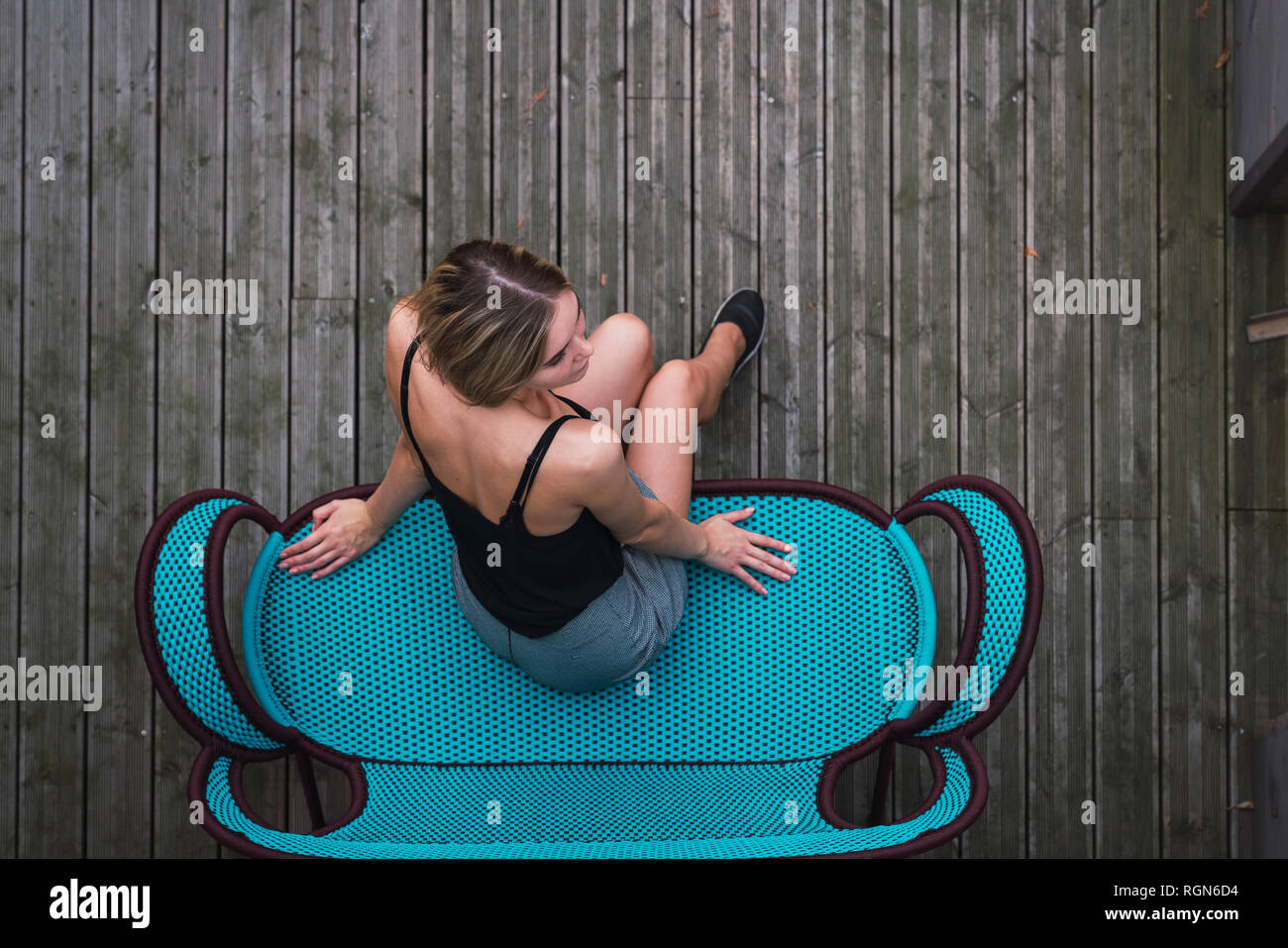 Junge Frau sitzt auf Türkis Tisch auf der Terrasse, Ansicht von oben Stockfoto
