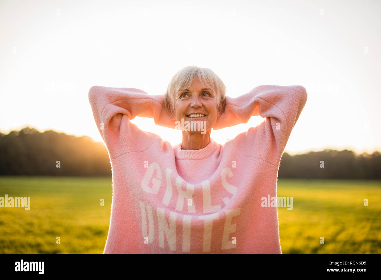 Portrait von zuversichtlich, ältere Frau, die auf den ländlichen Wiese bei Sonnenuntergang Stockfoto