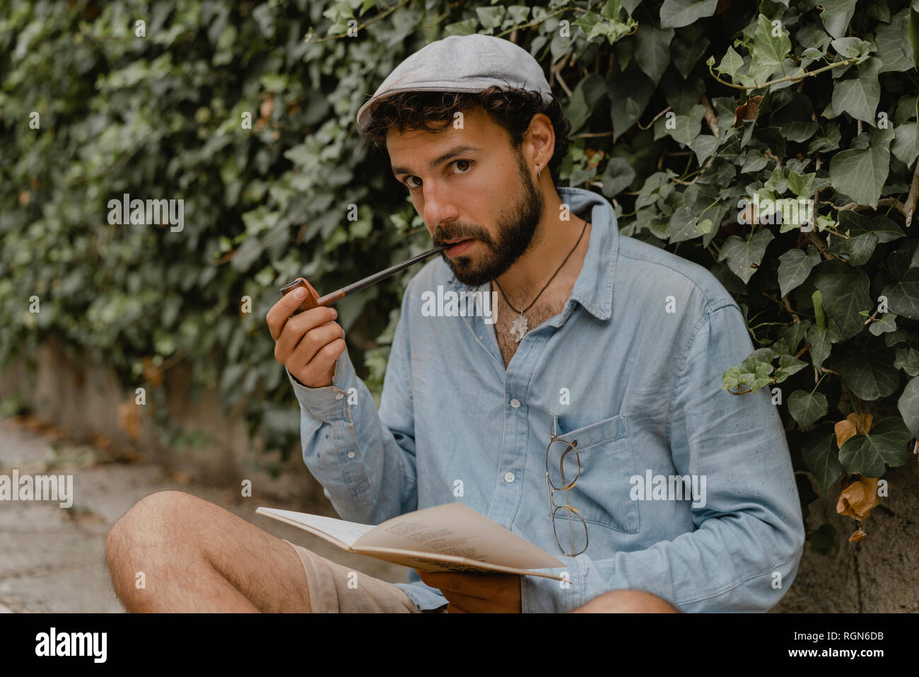Junger Mann rauchen Pfeife, ein Buch lesen Stockfoto