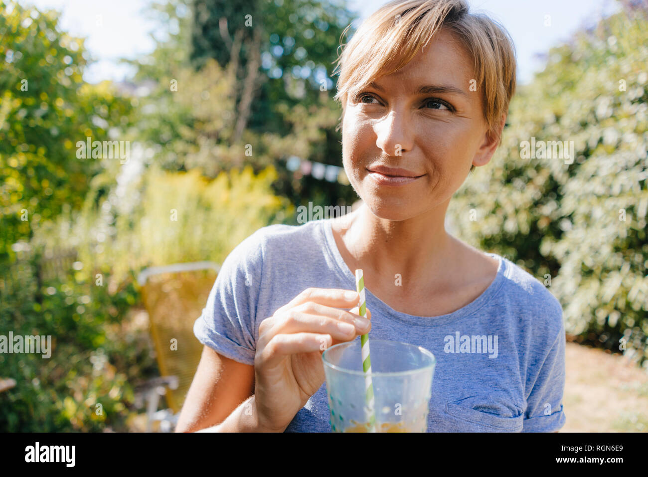 Portrait von Frau trinkt ein Getränk im Garten Stockfoto