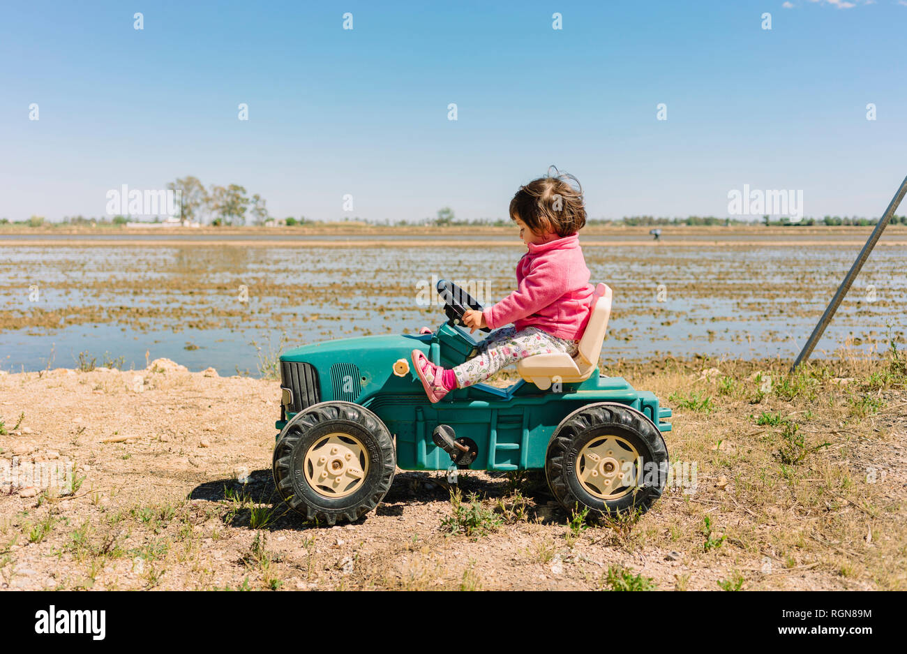 Baby Mädchen fahren ein Spielzeug Traktor neben den Reisfeldern  Stockfotografie - Alamy