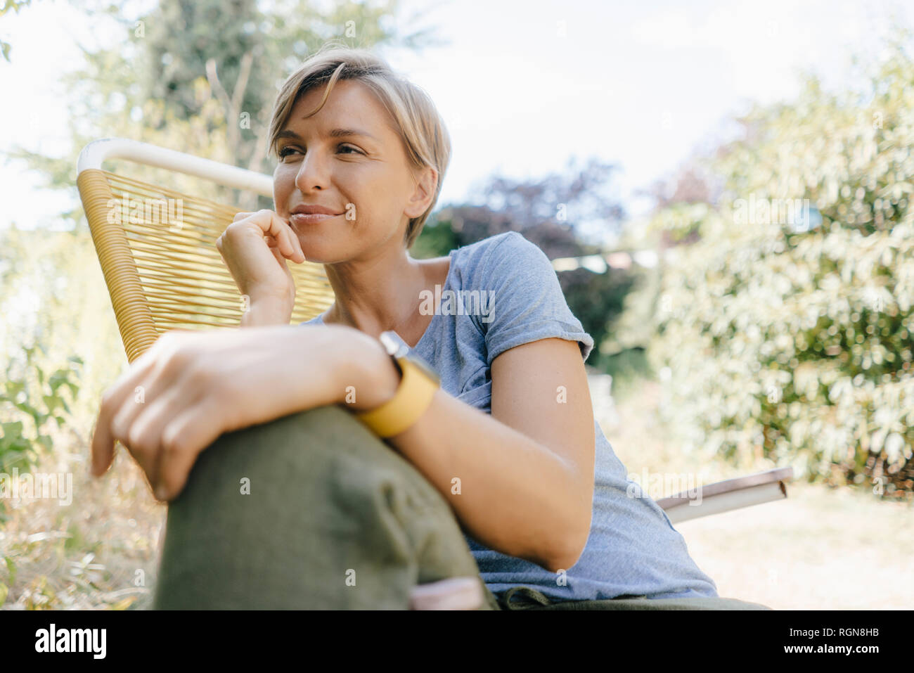Frau sitzt im Garten am Lehrstuhl Stockfoto