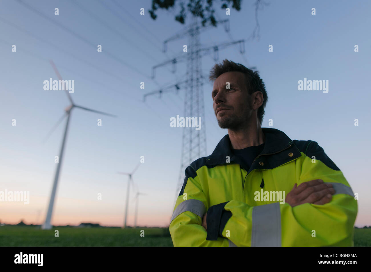 Porträt eines Ingenieurs neben einem Windpark und Strommast Stockfoto