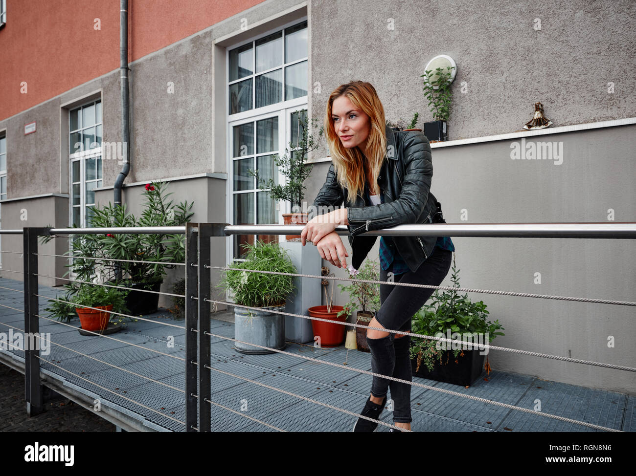 Selbstbewussten jungen Frau tragen Biker Jacke lehnte sich auf Balkon Geländer Stockfoto