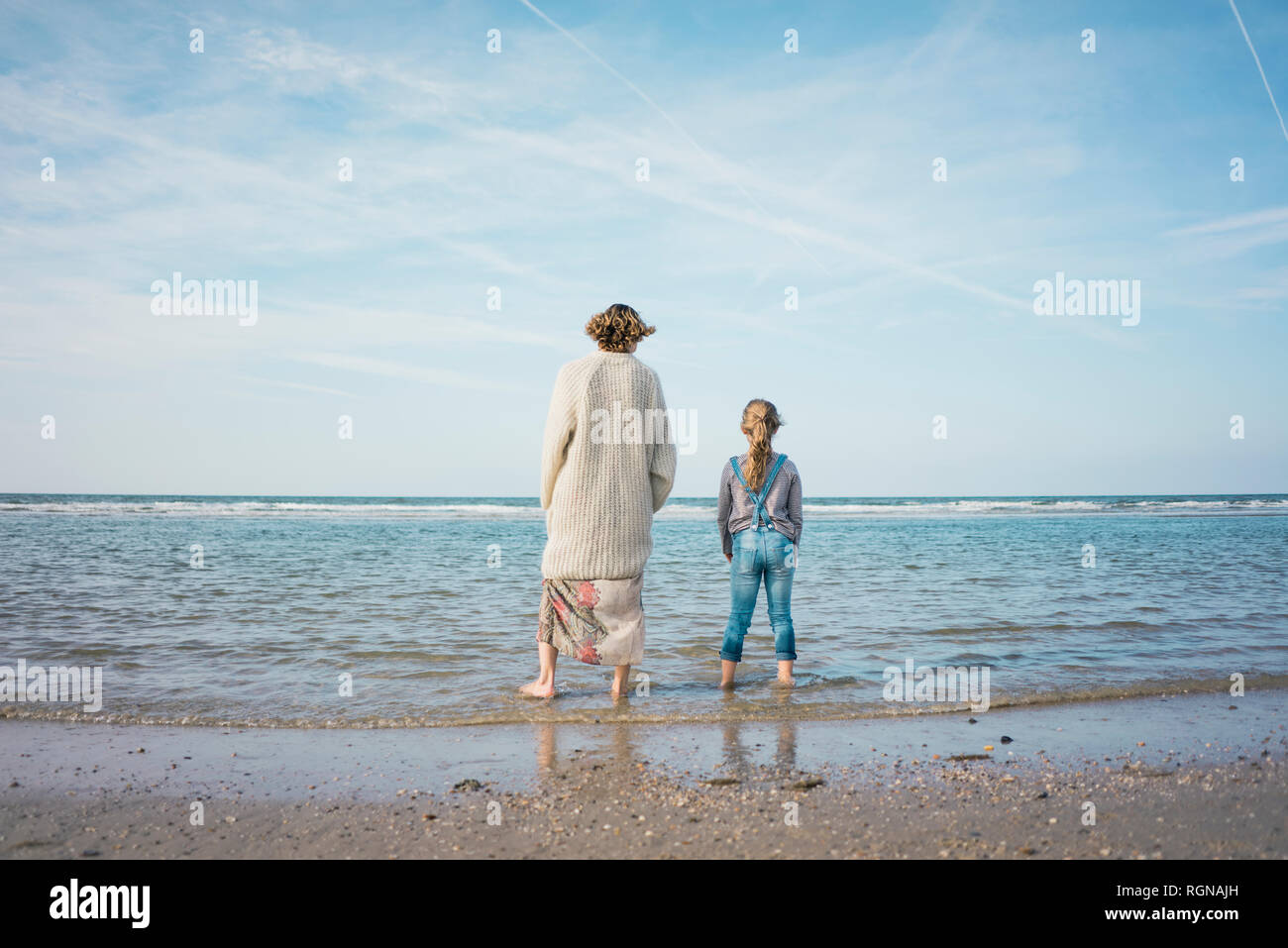 Mutter und Tochter stehen am Strand, am Meer suchen, Ansicht von hinten Stockfoto