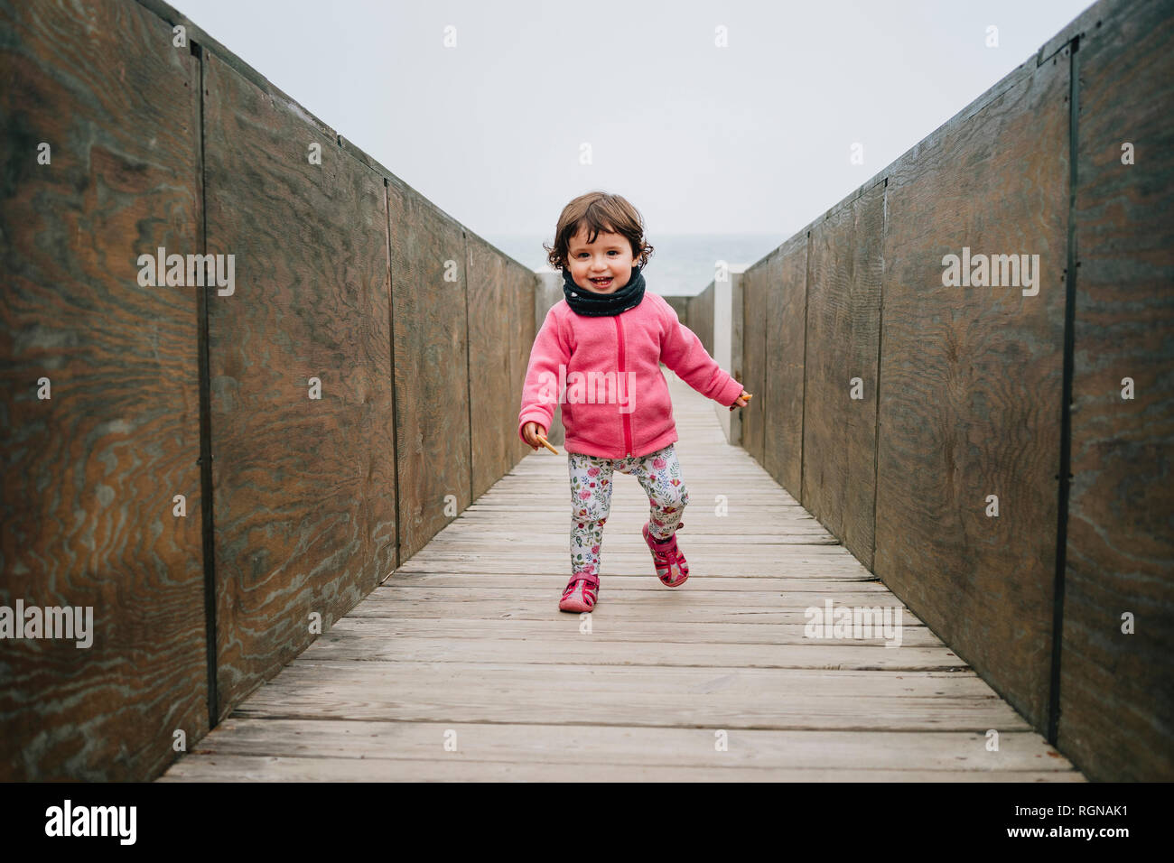 Baby Mädchen zu Fuß auf einem Holzsteg Stockfoto
